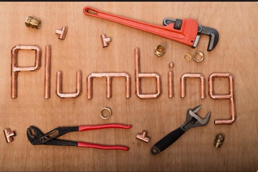 plumbing sign made of copper piping and shower plumbing tools like plumber's wrench and channel lock pliers