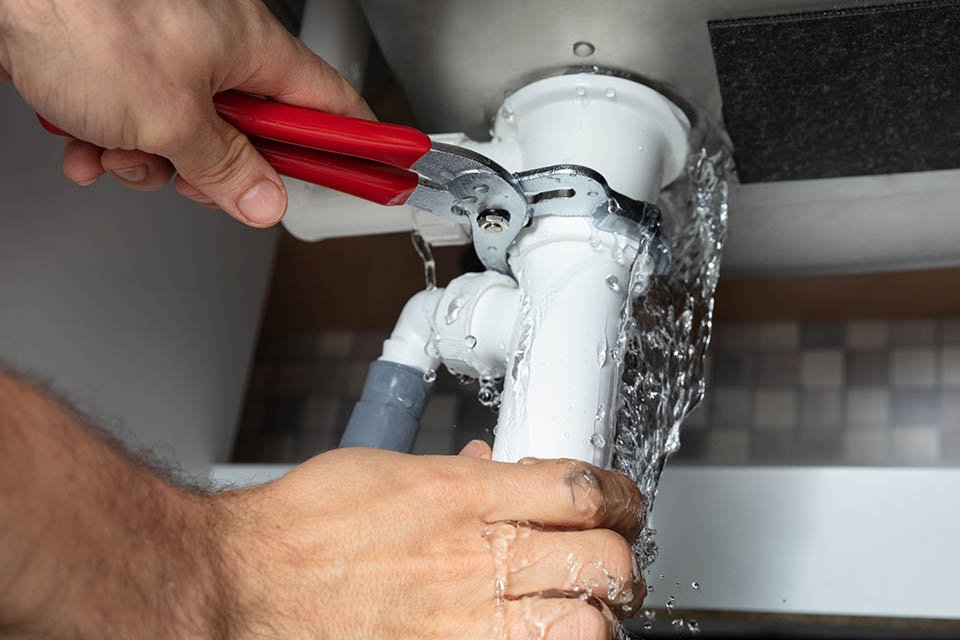 plumber fixing leak under sink